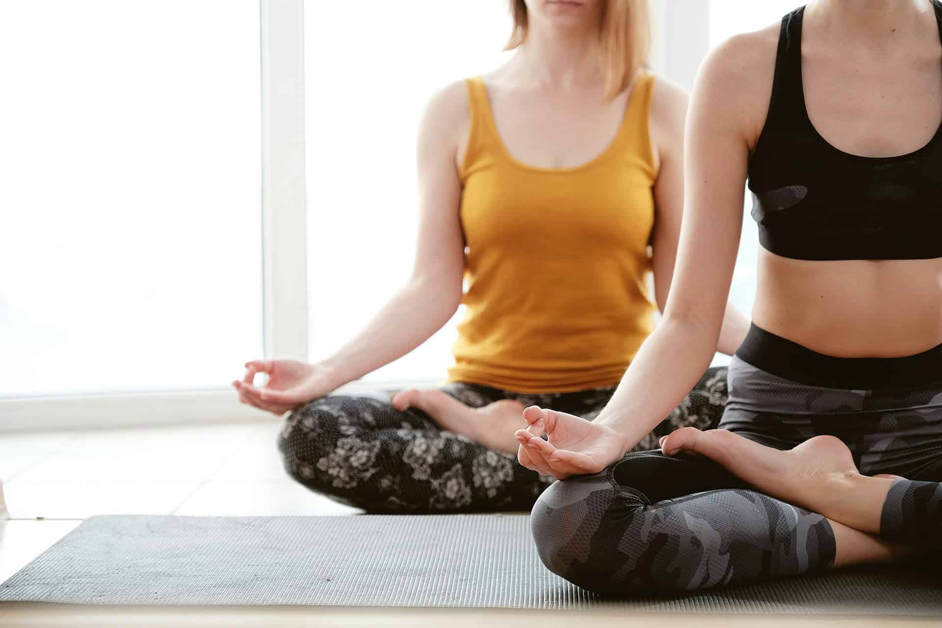 Two women practicing yoga in lotus position.