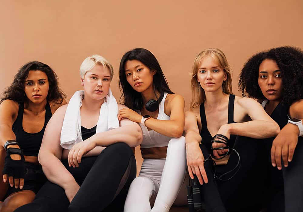 Five women in athletic wear sitting together.