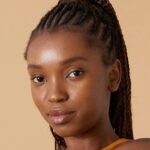 Woman with braided hair, neutral background.