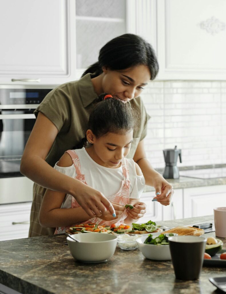 A mom and daughter share a bonding moment while preparing a healthy lunch together in the kitchen.