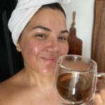 woman with towel on her head holding cup.